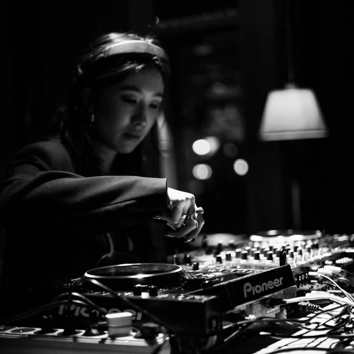 A woman djing at a soundboard in a dark room.